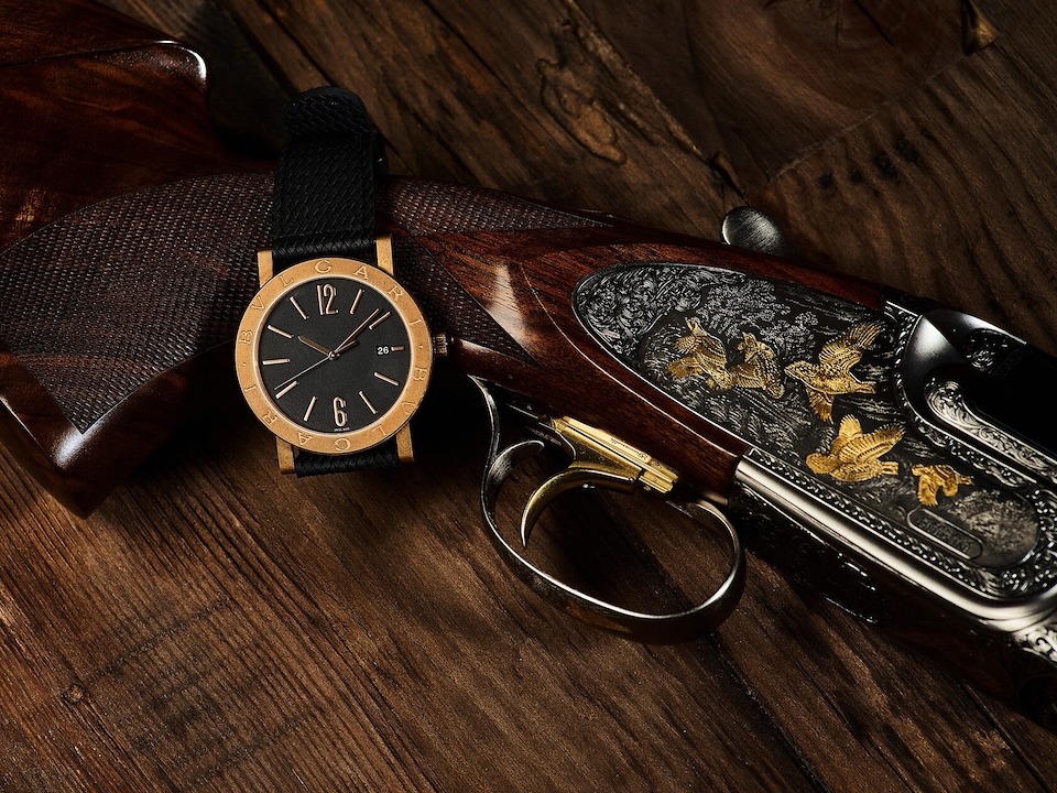Часы Bvlgari рядом с гравированным ружьём